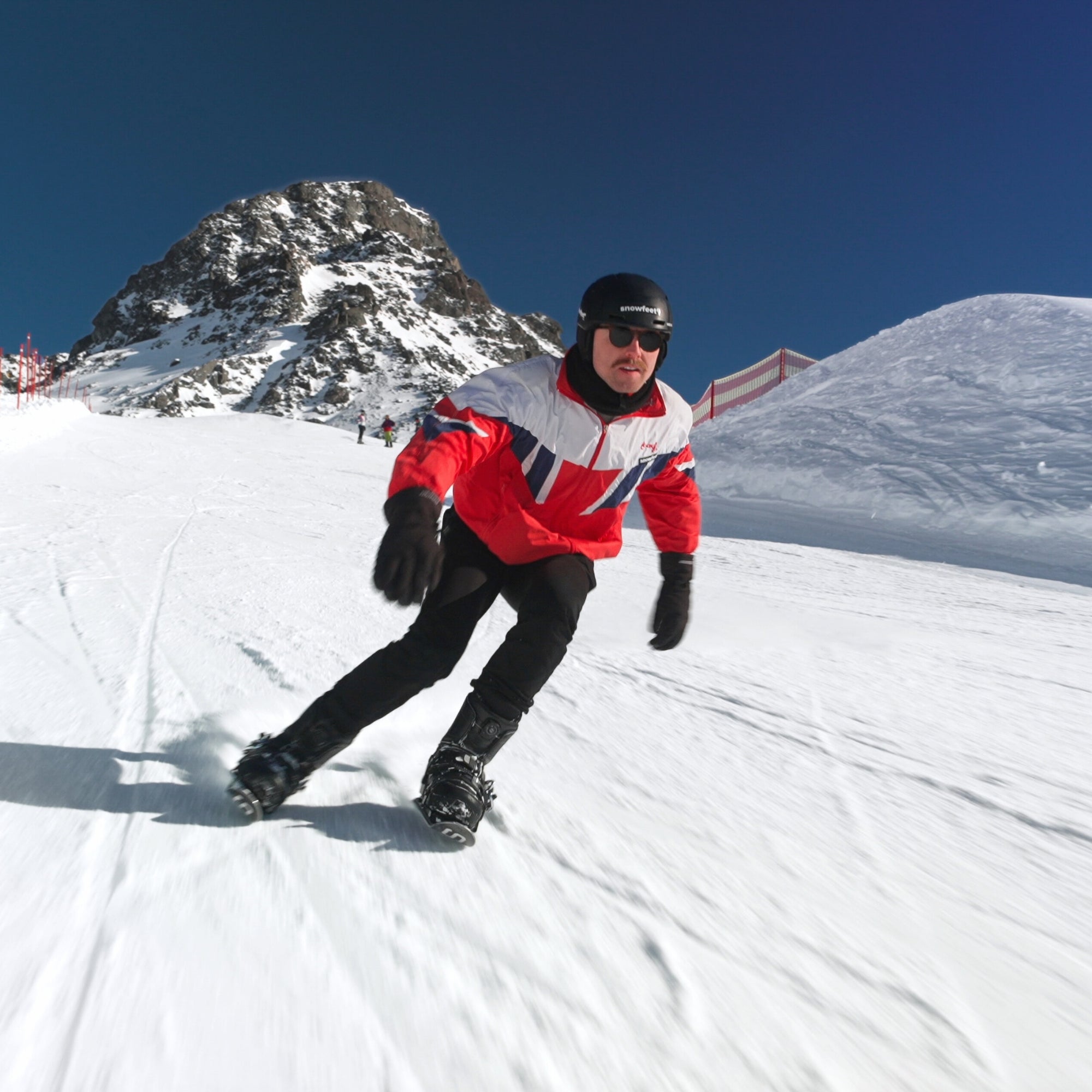 Person snowboarding on a snowy slope with mountains in the background