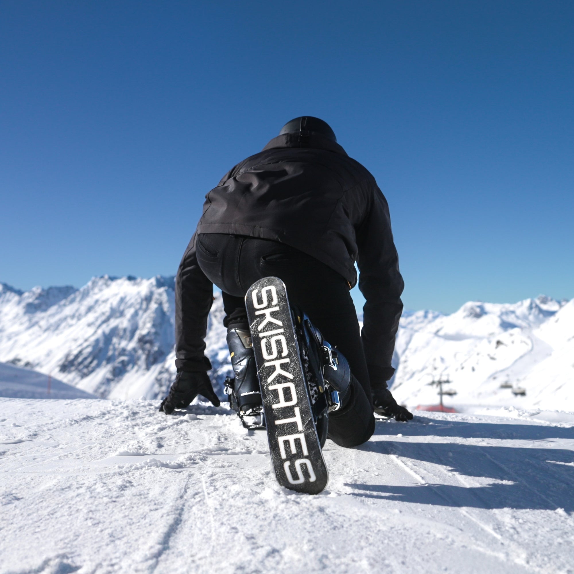 Person using a ski-kate on a snowy landscape with mountains in the background