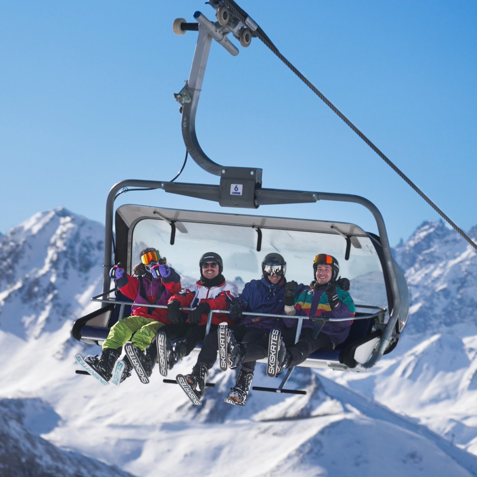 People on a ski lift with snowy mountains in the background