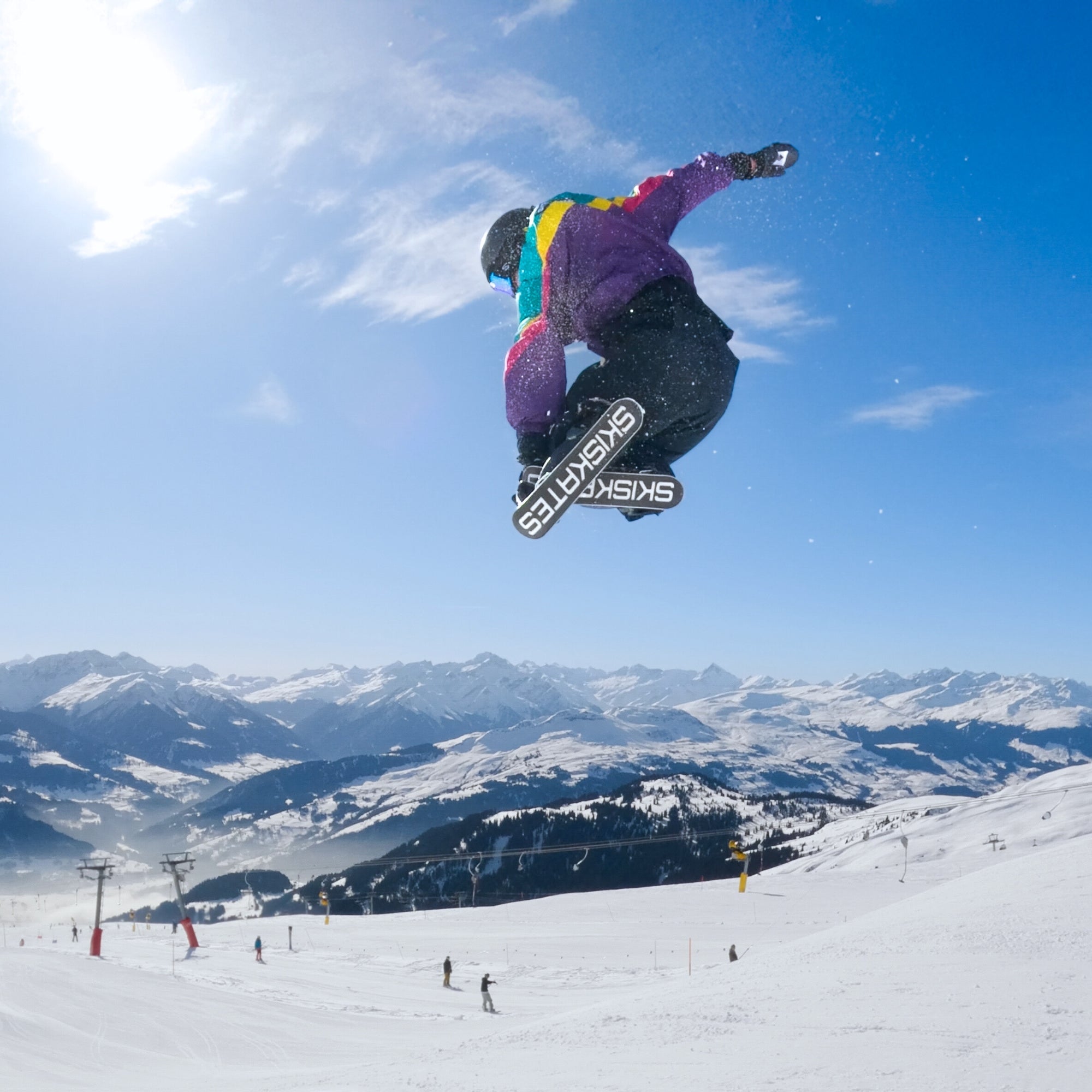 Person snowboarding in the air with a snowy mountain landscape in the background