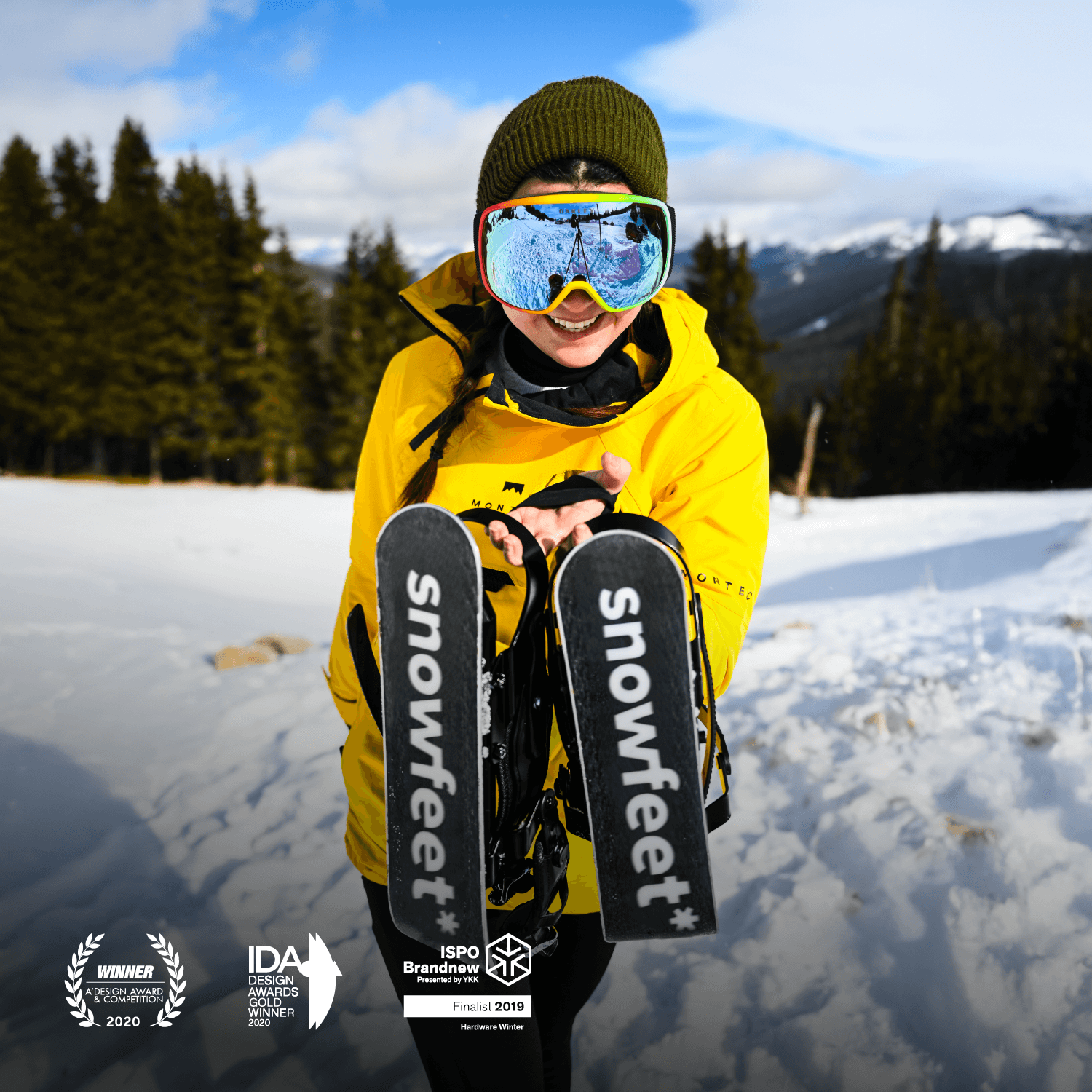 Person holding snowboards with 'snowfeet' branding in a snowy landscape
