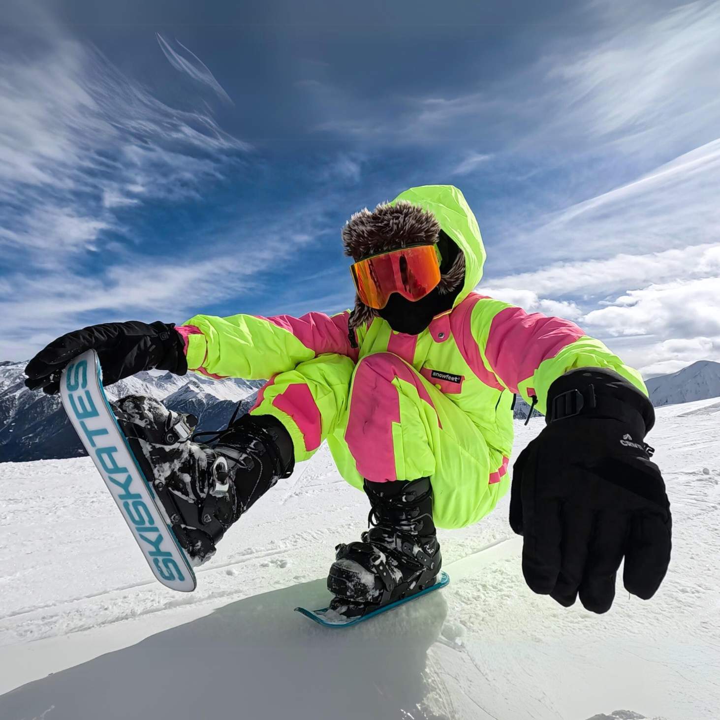 Person snowboarding in a bright jacket with a blue sky and mountains in the background